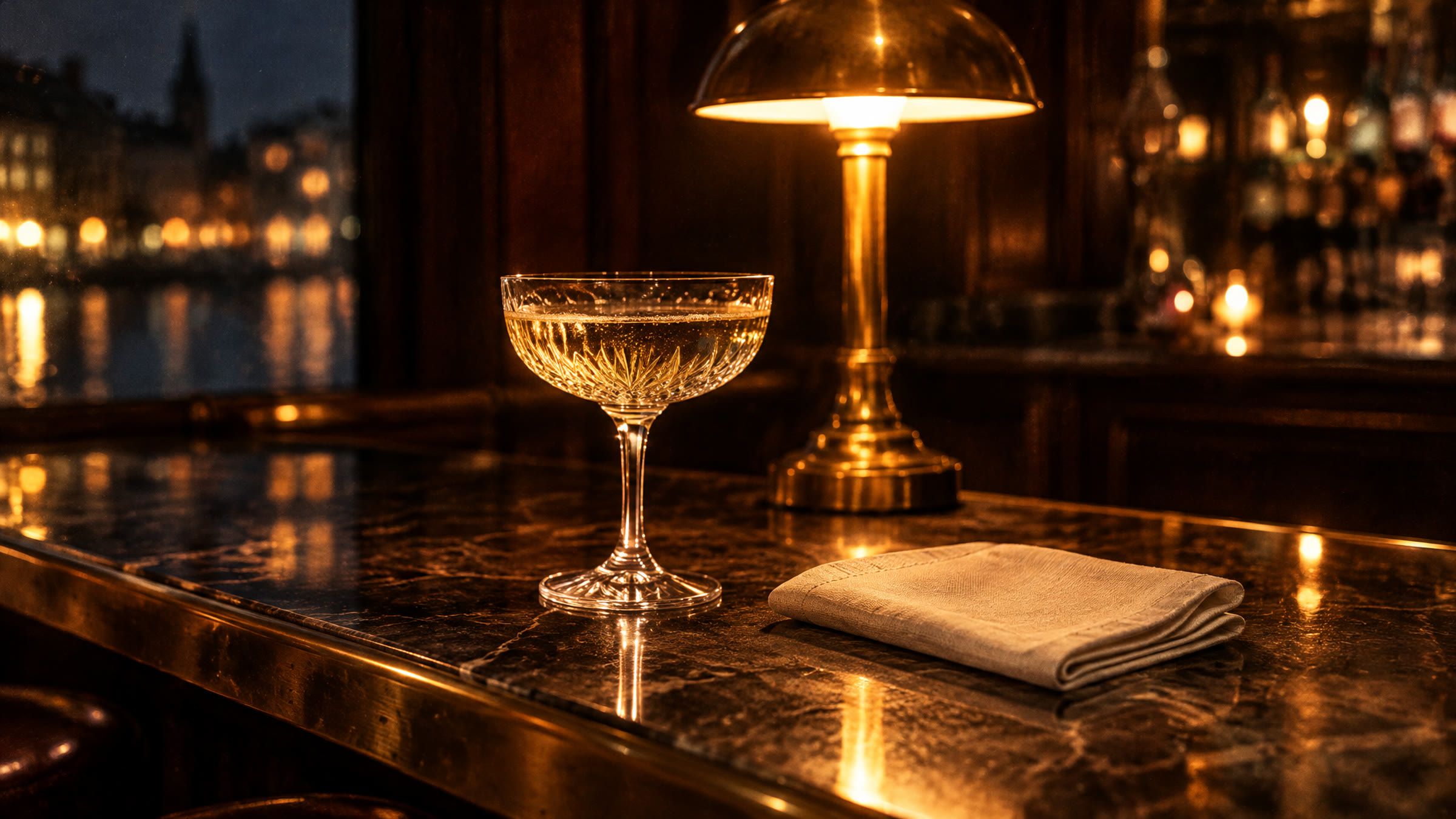 Et champagneglas og en foldet stofserviet på en marmordisk i en bar om aftenen.